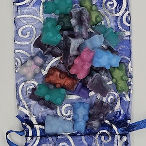 May include: A blue drawstring bag filled with colorful gummy bear shaped candies. The bag has a silver swirl pattern.