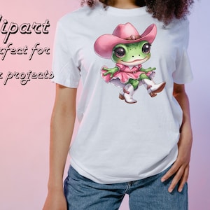 May include: White t-shirt featuring a cartoon frog wearing a pink cowboy hat, dress, and boots. The frog has large eyes and is sitting down. The shirt also has the text "Clipart Perfect for your projects" in pink.