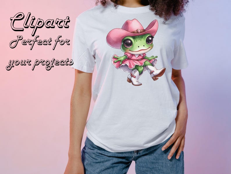 May include: White t-shirt featuring a cartoon frog wearing a pink cowboy hat, dress, and boots. The frog has large eyes and is sitting down. The shirt also has the text "Clipart Perfect for your projects" in pink.