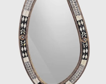 May include: An oval-shaped mirror with a decorative frame. The frame features a gold-colored trim with a pattern of black and white diamond shapes and circular accents. The mirror's shape is asymmetrical, adding a unique design element.