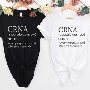 Op de afbeelding: Twee T-shirts met de tekst "CRNA (see.abr.en.ey) noun A very expensive and effective bartender" erop gedrukt. E&eacute;n T-shirt is zwart en de andere is wit.