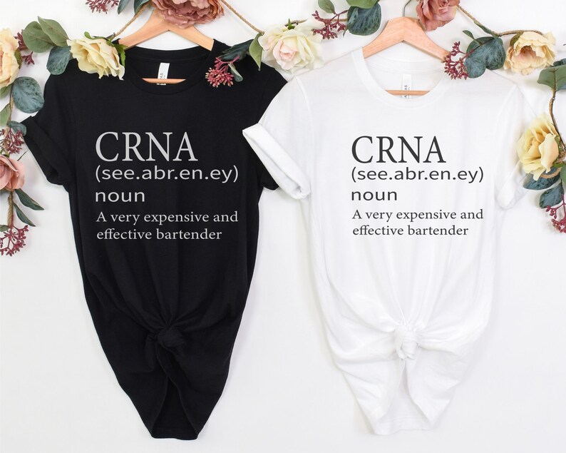 Op de afbeelding: Twee T-shirts met de tekst "CRNA (see.abr.en.ey) noun A very expensive and effective bartender" erop gedrukt. E&eacute;n T-shirt is zwart en de andere is wit.