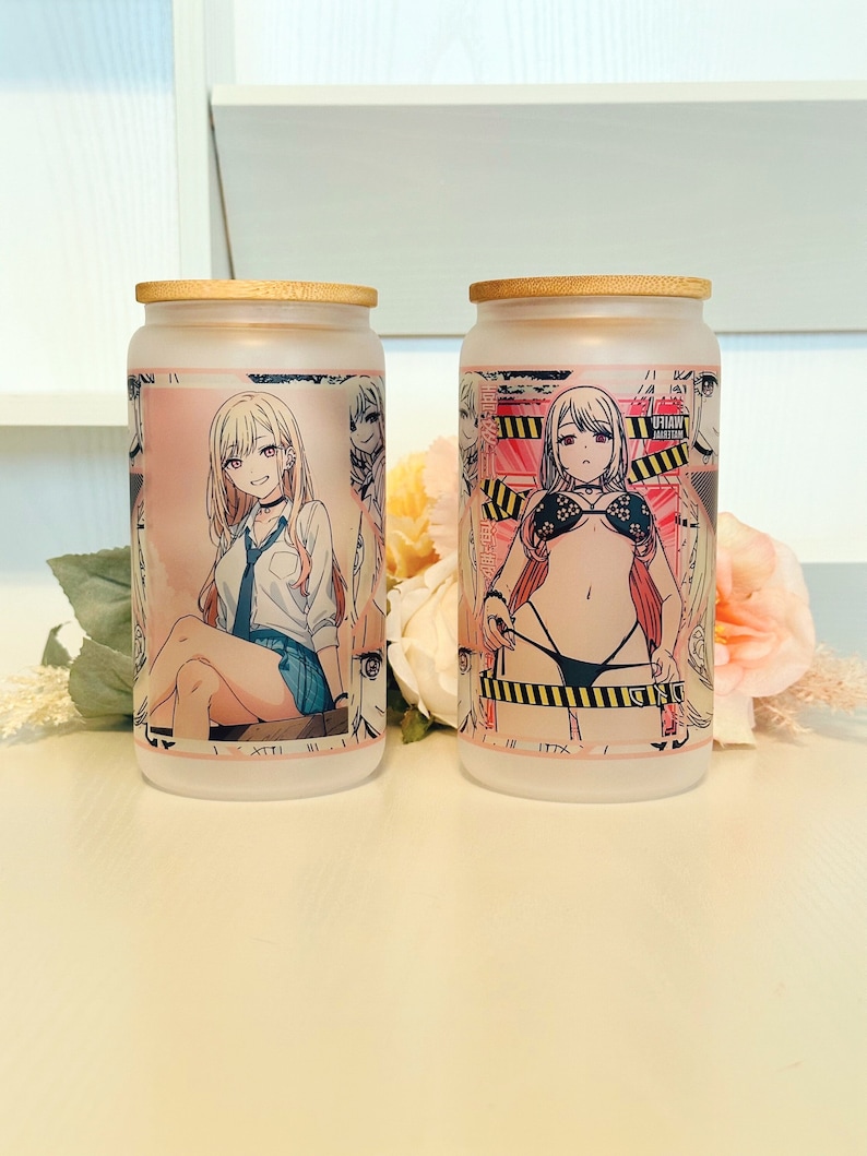 Puede incluir: Dos tarros de vidrio esmerilado con tapas de bamb&uacute;. Los tarros tienen im&aacute;genes de estilo anime de colores impresas en ellos. Un tarro presenta un personaje femenino con uniforme escolar, el otro presenta un personaje femenino en bikini.