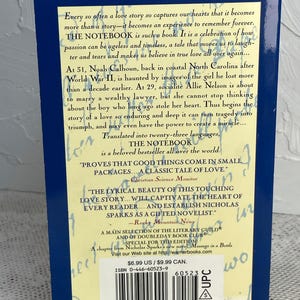 May include: A paperback copy of "The Notebook" by Nicholas Sparks. The book's back cover features text describing the story of Noah and Allie, set against a blue background. Includes quotes and a barcode.