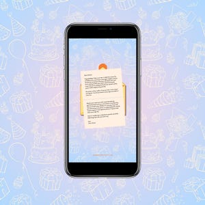 May include: A smartphone displays a birthday card with a handwritten message. The card is in an open envelope, set against a light blue background with white line drawings of birthday cakes, gifts, and balloons. The phone's screen is black.