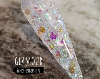 May include: A clear nail dip with iridescent glitter and small, colorful glitter. The text "GLAMOUR" and "FANCYFINGERSDIPS" is visible below the nail dip.