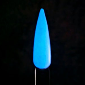May include: A single, glowing blue nail tip against a black background. The nail is a vibrant, light blue color, and appears to be illuminated from within. The nail is mounted on a thin, black stick.