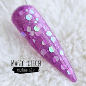 Puede incluir: Esmalte de uñas morado con purpurina iridiscente y purpurina hexagonal. El esmalte de uñas se llama "Magic Potion" de FancyFingersDips.
