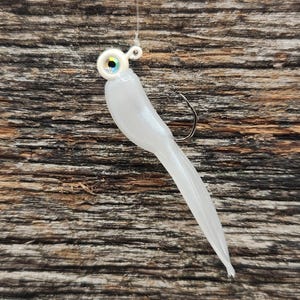 May include: White soft plastic fishing lure with a silver hook and a clear iridescent eye.
