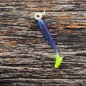 May include: Purple and green soft plastic fishing lure with a white bead and a silver hook.