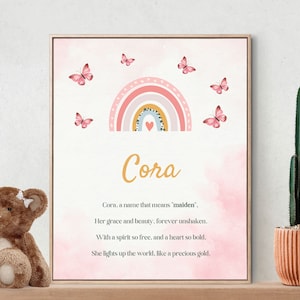 May include: A pink and yellow rainbow with a heart in the centre, surrounded by pink butterflies. The name "Cora" is written in gold script below the rainbow. The text below reads: "Cora, a name that means 'maiden'. Her grace and beauty, forever unshaken. With a spirit so free, and a heart so bold. She lights up the world, like a precious gold."
