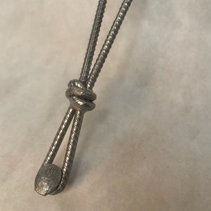 Peut inclure: Une patte de table en métal avec un design noué. La patte est composée de deux morceaux de ferraille soudés ensemble en haut et en bas. Le nœud est un élément décoratif qui ajoute une touche unique à la patte.