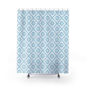 May include: A light blue and white patterned shower curtain. The design features a repeating floral motif arranged in a diamond grid. The curtain is hanging from a metal rod with silver hooks. The overall theme is bathroom decor.