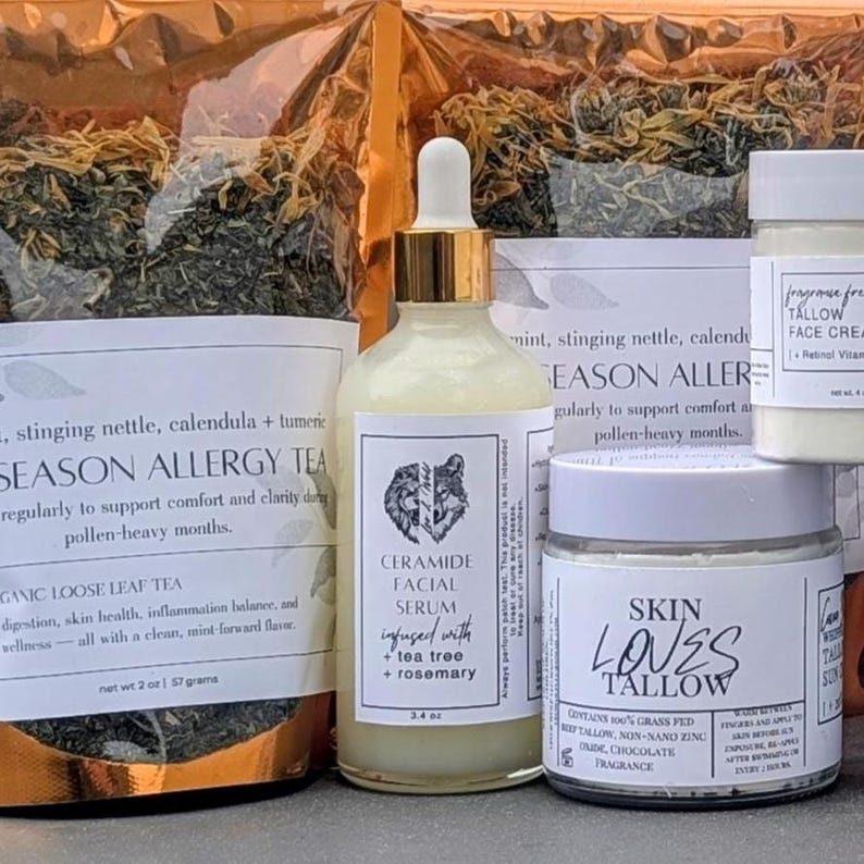 May include: An assortment of natural skincare products and herbal tea. The image features a glass bottle of Ceramide Facial Serum, a jar of Skin Loves Tallow, and a bag of Season Allergy Tea. The serum is infused with tea tree and rosemary.