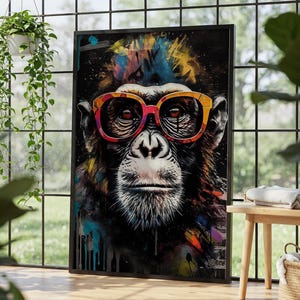 Puede incluir: Una impresión artística enmarcada que presenta un chimpancé con gafas coloridas. La cara del chimpancé está detallada con pelaje blanco y una expresión seria. El fondo es una mezcla de colores vibrantes, incluyendo azul, amarillo y rojo.