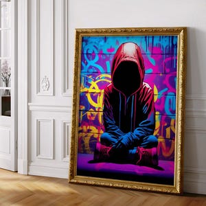 Könnte beinhalten: Ein gerahmter Kunstdruck mit einer Figur in einem roten Kapuzenpullover mit schwarzem Gesicht vor einer Graffiti-Wand. Das Kunstwerk hat einen goldenen Rahmen und verwendet leuchtende Farben, darunter Blau, Lila und Gelb.