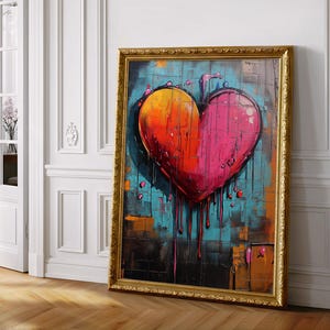 May include: A rectangular framed painting featuring a large, central heart shape with a gradient of yellow, orange, and pink. The heart appears to be dripping paint over a textured, multi-colored background of blue, black, and brown geometric blocks.