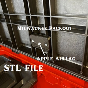 May include: A black 3D printed holder for an Apple AirTag, designed to fit inside a Milwaukee Packout toolbox. The holder is attached to the inside of the toolbox lid with two screws. The text "STL FILE" is visible in the image.