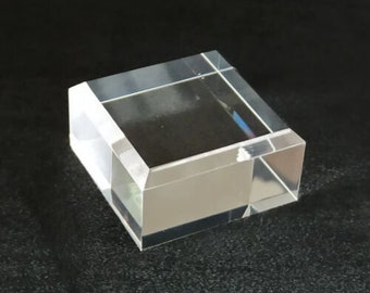 Könnte beinhalten: Ein transparenter Acryl-Präsentationsständer mit quadratischer Basis und rechteckiger Oberseite. Der Ständer ist aus dickem, strapazierfähigem Acryl gefertigt und eignet sich perfekt zum Präsentieren kleiner Gegenstände.