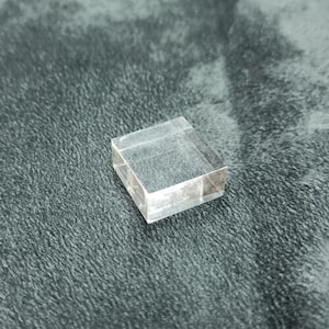 Könnte beinhalten: Ein transparenter Acryl-Präsentationsständer, perfekt für die Präsentation kleiner Gegenstände wie Schmuck, Figuren oder Kristalle.