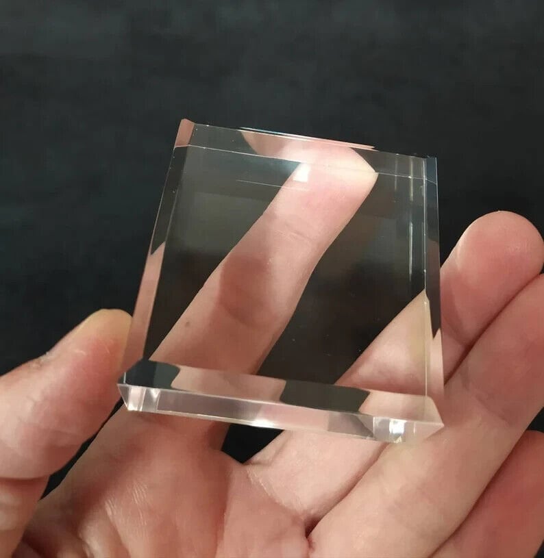 May include: A clear glass paperweight with beveled edges.