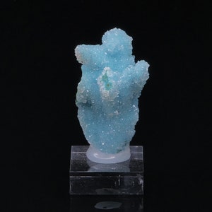 Peut inclure: Un spécimen minéral bleu cristallin avec une forme organique unique. Le minéral est présenté sur un support en acrylique transparent.