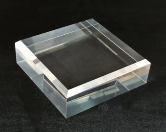 Könnte beinhalten: Ein quadratischer Acryl-Präsentationsständer mit abgeschrägten Kanten. Der Ständer ist perfekt für die Präsentation kleiner Gegenstände wie Schmuck, Figuren oder anderer Sammlerstücke.