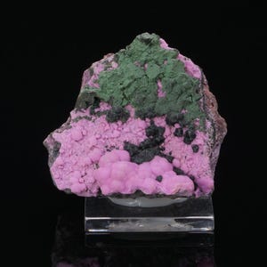 May include: A colourful mineral specimen with a mix of textures. The top section has a textured, dark green area, while the lower part shows a bubble-like, bright pink formation. Black accents are scattered throughout the piece.