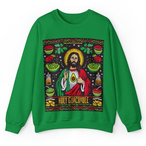 Può includere: Felpa verde con un design natalizio che presenta un'immagine di cartone animato di Gesù che tiene un avocado con il testo "HOLY GUACAMOLE".