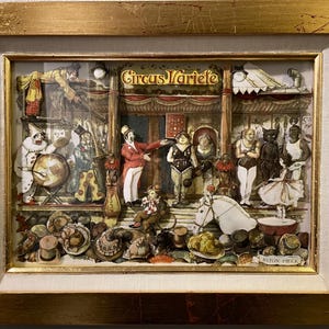 May include: A framed paper mache artwork depicting a circus scene with a variety of characters, including clowns, a ringmaster, and a horse. The artwork is titled "Circus Varieté" and includes the text "En fin pièce".