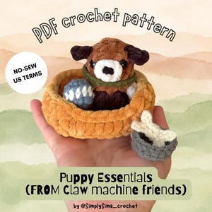 Puede incluir: Un cachorro de ganchillo en una cama color canela con una pelota azul, un cuenco gris y un hueso blanco. Texto: PDF crochet pattern, NO-SEW US TERMS, Puppy Essentials (FROM Claw machine friends) by @SimplySima_crochet. El cachorro es marrón, blanco y negro.
