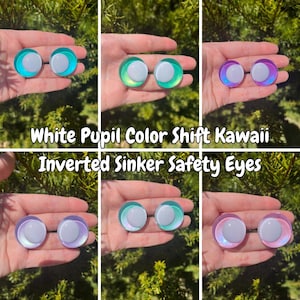 May include: A collection of six pairs of inverted sinker safety eyes with white pupils and color shift kawaii designs. The eyes are shown in various colors, including teal, green, and purple. Text on the image reads "White Pupil Color Shift Kawaii Inverted Sinker Safety Eyes."
