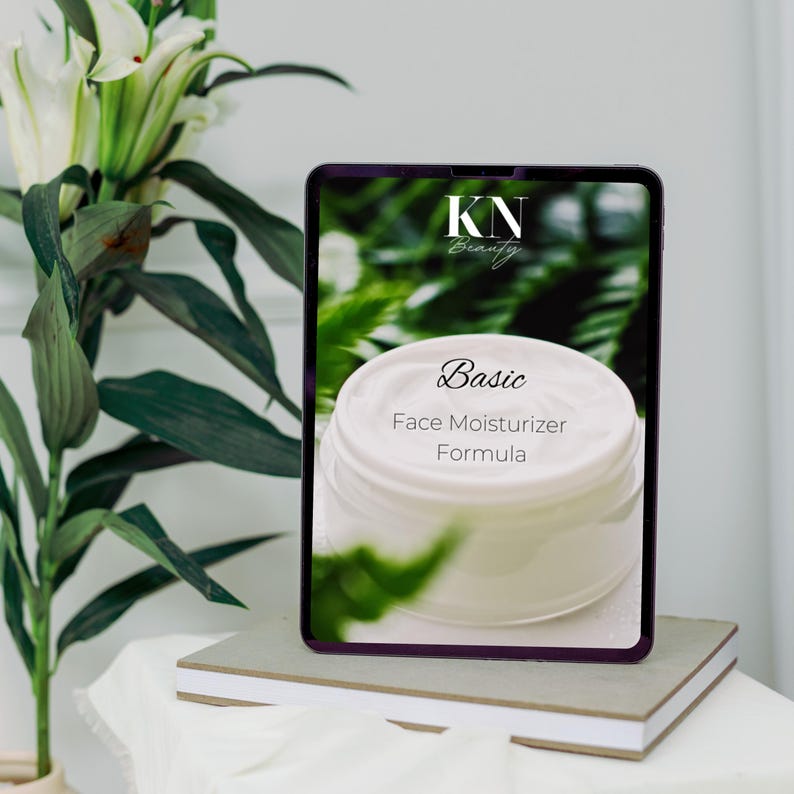 以下が含まれることがあります： 緑色の背景に「Basic Face Moisturizer Formula」というテキストと「KN Beauty」のロゴが書かれた白い顔用保湿クリームの瓶が表示されているデジタルタブレットです。