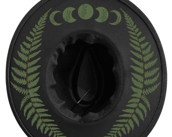 May include: Black fedora-style hat with a wide brim. The hat features a green fern design around the brim and moon phase graphics. The interior is black with a structured crown. A stylish accessory for outdoor wear.