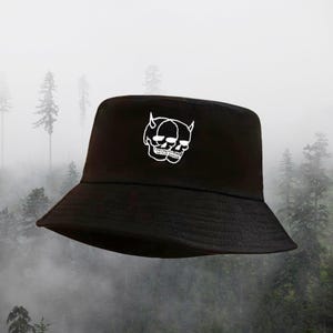 May include: Black bucket hat with a white embroidered design of two skulls with horns.