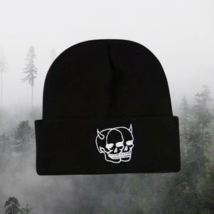 May include: Black beanie with a white embroidered design of two skulls with horns.