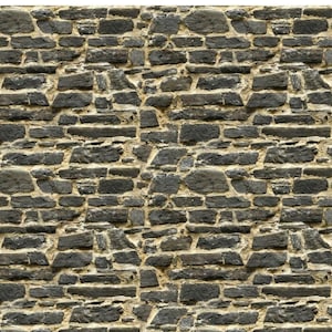 Puede incluir: Un primer plano de un muro de piedra con una textura rugosa y desigual. Las piedras son de una mezcla de gris oscuro y marrón, con algo de mortero gris más claro entre ellas. El muro está hecho de piedras de forma irregular, creando un aspecto rústico y natural.