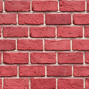 Op de afbeelding: Close-up van een rode bakstenen muur met witte mortel. De bakstenen zijn rechthoekig en hebben een licht ruwe textuur. De muur is gelijkmatig verlicht en toont de details van het metselwerk.