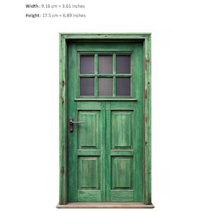 Op de afbeelding: Een groene houten deur met een glazen paneel verdeeld in zes vierkanten. De deur heeft een metalen handvat en is omlijst met een houten lijst. Een liniaal is zichtbaar aan de onderkant van de afbeelding.