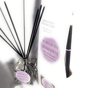 May include: A clear glass bottle with a square base filled with lavender scented diffuser oil. The bottle is surrounded by black and gray reed sticks. The label on the bottle reads "BFC Reed Diffuser Lavender Scented 100ml Glass Curved Bottle & 8 x 240mm Black Fibre Reeds".