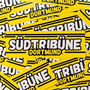 Könnte beinhalten: Ein gelber Aufkleber mit schwarzen Streifen und weißem Text, der "Südtribune Dortmund" lautet.