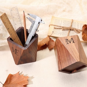 May include: Two wooden desk organizers with geometric designs. One holds a ruler, pencil, and caliper. The other has the name "Matthew" engraved on it. The organizers are made of dark wood and sit on a neutral surface.