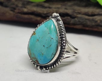May include: A silver ring with a teardrop-shaped turquoise stone set in a silver bezel. The ring has a braided band.