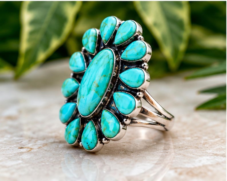 Puede incluir: Un anillo de plata con una gran piedra turquesa ovalada central rodeada por doce piedras turquesas m&aacute;s peque&ntilde;as en forma de l&aacute;grima. Las piedras est&aacute;n engastadas en biseles de plata pulida con un dise&ntilde;o de banda de v&aacute;stago dividido.
