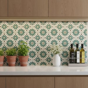 Peut inclure: Plan de travail de cuisine avec trois plantes de basilic en pot, un vase blanc avec des fleurs et un présentoir métallique contenant trois bouteilles d'huile d'olive. La crédence est ornée de carreaux à motifs verts, blancs et marron.