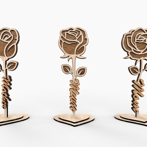 May include: Three wooden rose cutouts with the word "Mom" written on the stem of each rose. The roses are standing on heart-shaped bases.