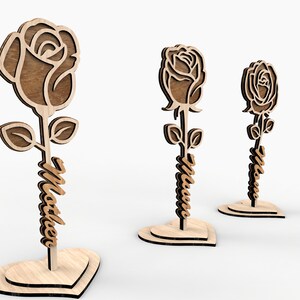 May include: Three wooden rose cutouts with the names "Maddie", "Olivia", and "Nora" written on the stems. The roses are standing on heart-shaped bases.