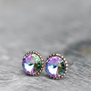Puede incluir: Un par de pendientes de botón de plata con piedras preciosas iridiscentes de color púrpura y verde.