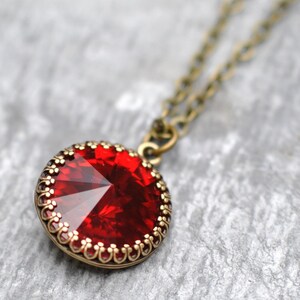 May include: A red gemstone pendant necklace with a gold-toned chain and a decorative filigree border around the stone.