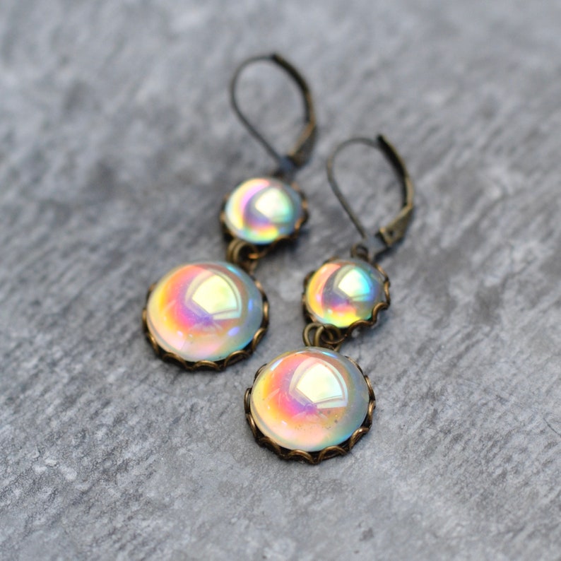 May include: A pair of iridescent glass earrings with a bronze finish. Each earring features two round glass beads with a delicate wire frame.